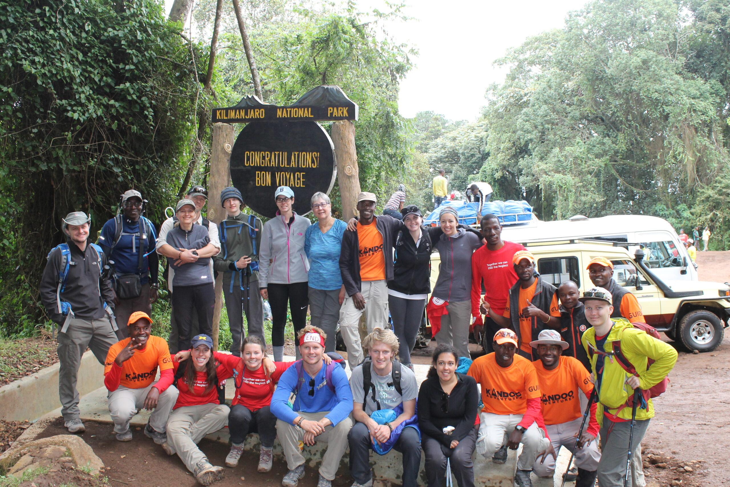 Climbers pose in front of sign congratulating their efforts.